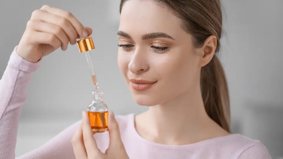 Woman examining a dropper bottle of a cosmetic product